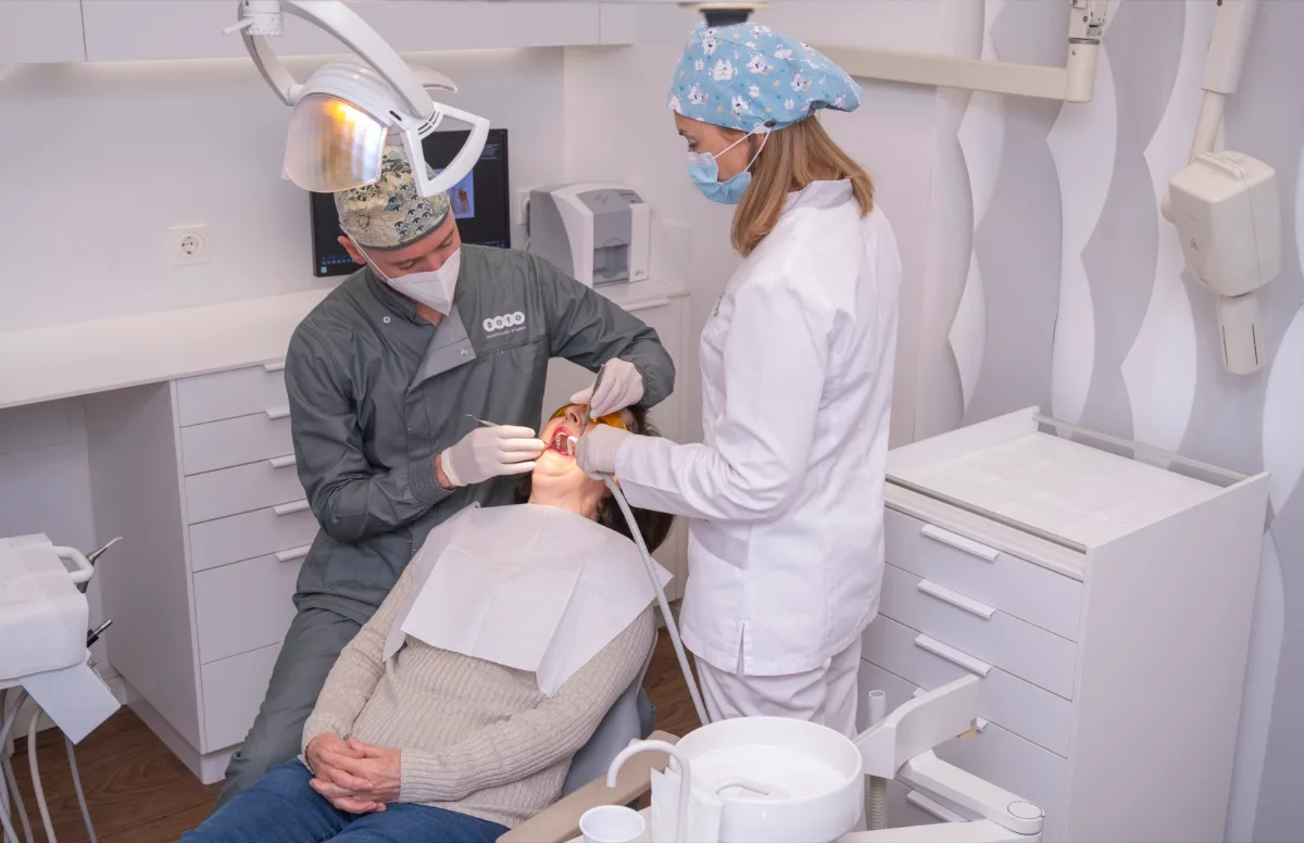 Dentista y auxiliar de Clínica Dental Soto realizando un empaste a una paciente en la consulta