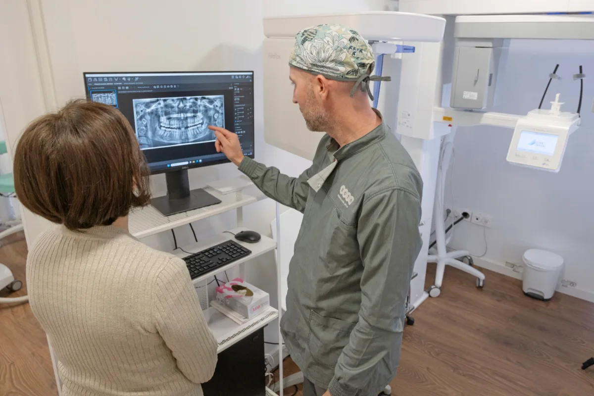 Dentista de Clínica Dental Soto mostrando a una paciente su radiografía panorámica para revisar los implantes dentales